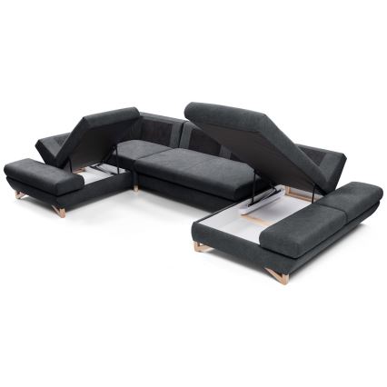 Rohová sedačka s otvorenými úložnými priestormi. Sedačka je tmavosivá s drevenými nožičkami. Úložné priestory sú umiestnené pod sedacími časťami. Sedačka stojí na bielom pozadí.