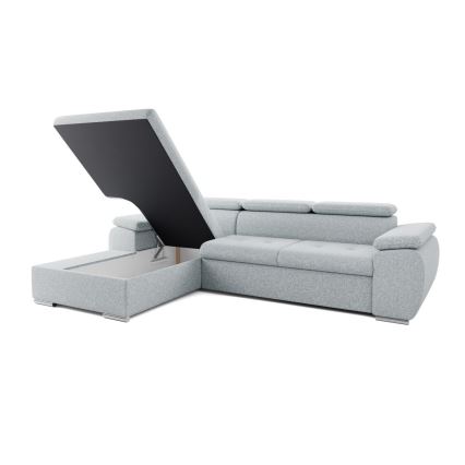 Rohová sedačka má otvorený úložný priestor s výklopným vrchnákom. Sedačka je svetlosivá, umiestnená na bielom pozadí.