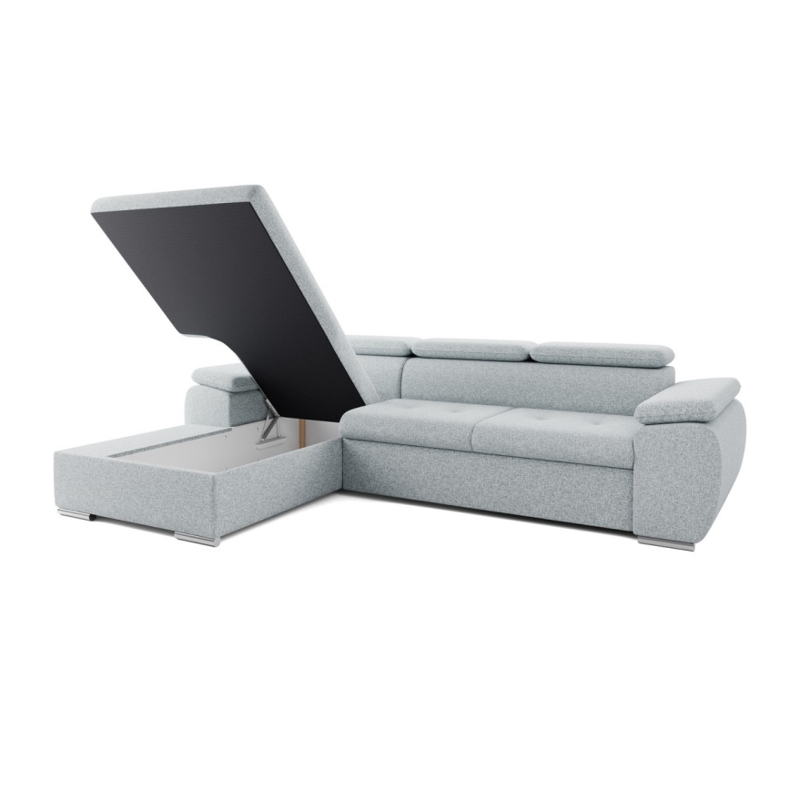 Rohová sedačka má otvorený úložný priestor s výklopným vrchnákom. Sedačka je svetlosivá, umiestnená na bielom pozadí.