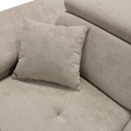 Vankúš leží na svetlohnedej sedačke. Sedačka je čalúnená textíliou s jemnou štruktúrou. V pozadí sú viditeľné ďalšie vankúše.