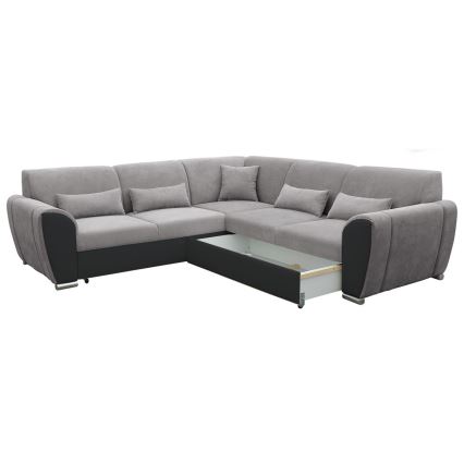 Rohová sedačka s výsuvným úložným priestorom je umiestnená na bielom pozadí. Sedačka je prevažne sivá, s čiernymi detailmi a niekoľkými vankúšmi.