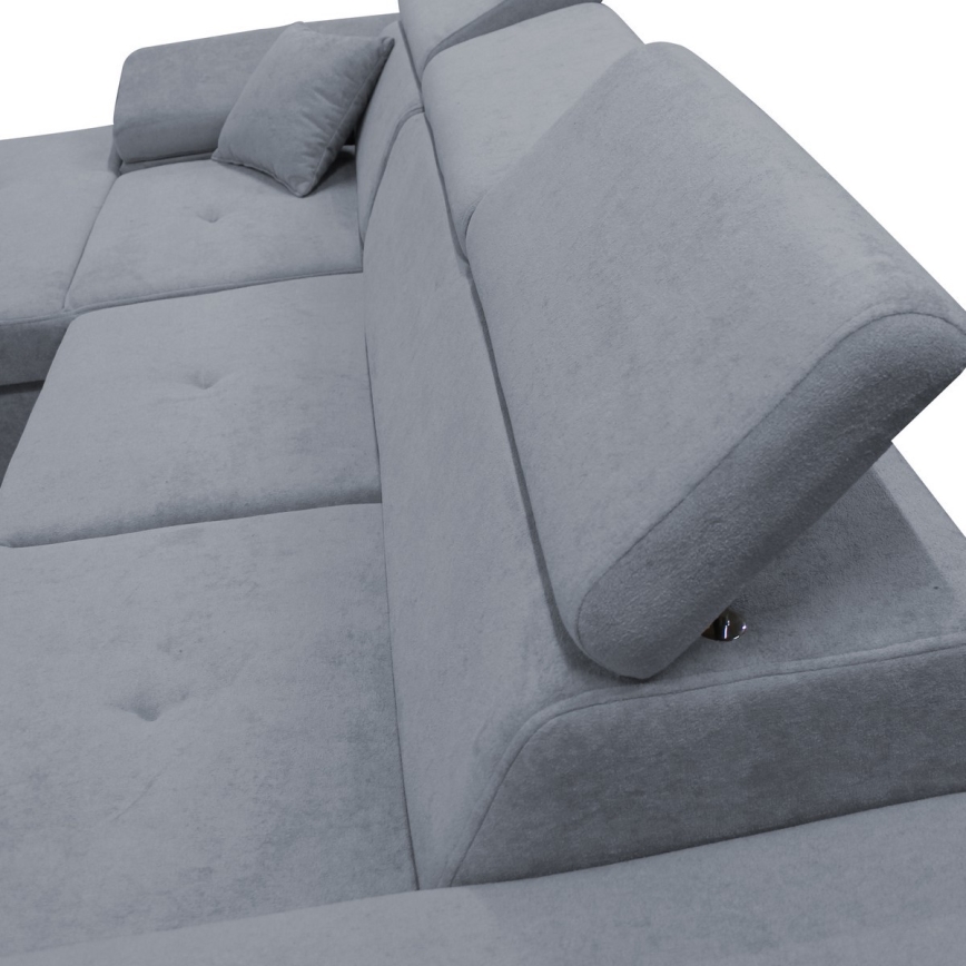 Rohová sedačka s opierkami hlavy je položená na bielom pozadí. Opierky sú nastaviteľné pomocou kovových mechanizmov. Sedačka je svetlosivá a čalúnená.