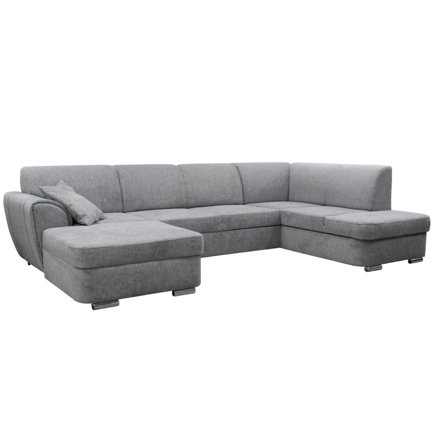 Rohová sedačka sivohnedej farby stojí v moderne zariadenej obývacej izbe s drevenou podlahou, kobercom a konferenčným stolíkom. Sedačka má ľavý roh a je doplnená o vankúš.