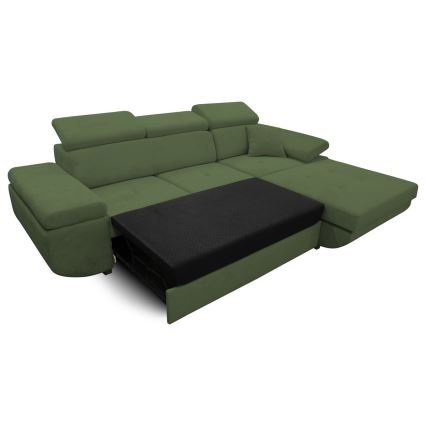 Rohový gauč olivovozelenej farby s výsuvnou časťou na spanie je zobrazený na bielom pozadí. Výsuvný mechanizmus je čiastočne vysunutý, odhaľujúc čiernu matrac.