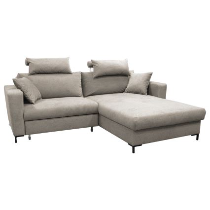 Rohová sedačka svetlo béžovej farby stojí v svetlej obývacej izbe. Sedačka má niekoľko vankúšov a je umiestnená na koberci s tmavosivým vzorom. Pred sedačkou sa nachádza biely konferenčný stolík.