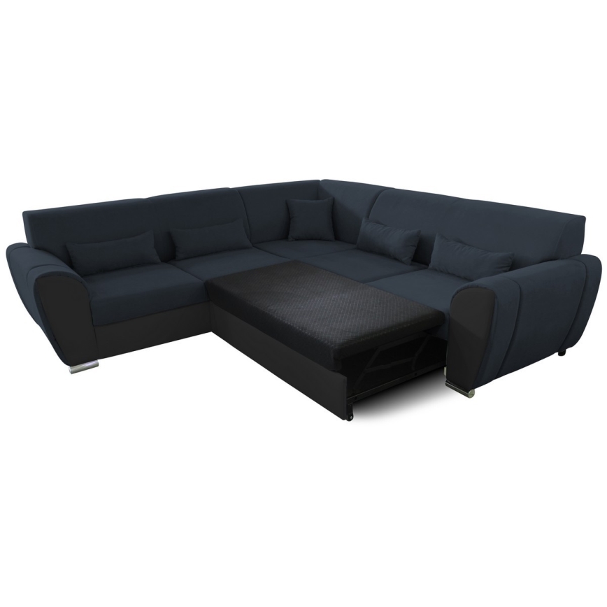 Rohová sedačka s rozkladacím lôžkom je v tmavomodrej látke s čiernymi detailmi. Lôžko je čiastočne vysunuté. Sedačka má niekoľko vankúšov a stojí na bielom pozadí.