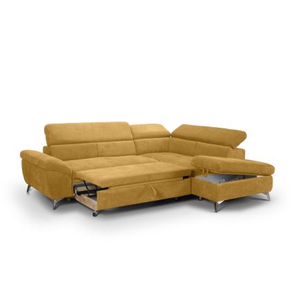 Rohová sedačka horčicovej farby s rozkladacím mechanizmom a úložným priestorom je umiestnená na bielom pozadí. Sedačka má pripojený menší taburet s úložným priestorom.