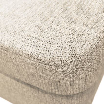 Čalúnená časť nábytku, pravdepodobne sedák, je vyrobená z béžovej textílie s jemnou textúrou. Je zhotovená z materiálu s viditeľným prepletením vlákien. Zobrazený je detail povrchu.