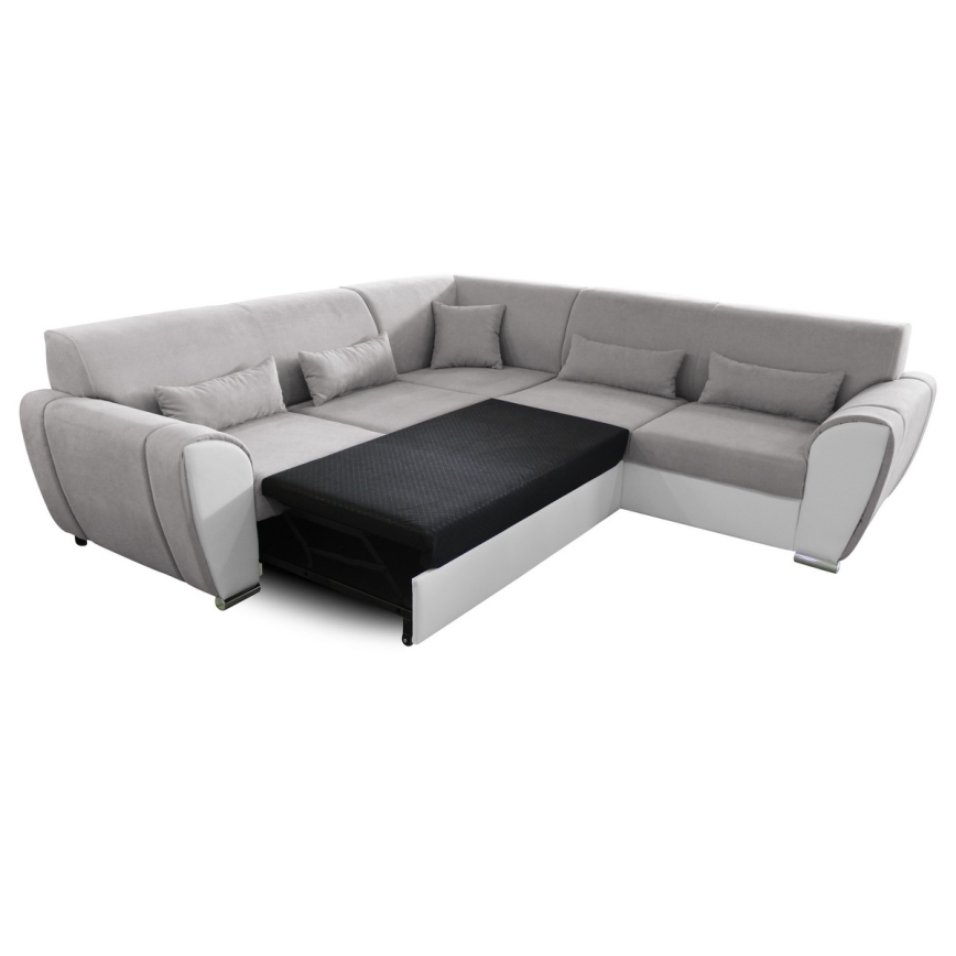 Rohová sedačka s výsuvným lôžkom je v sivej a bielej farbe. Sedačka má niekoľko vankúšov. Výsuvný mechanizmus je čiastočne vysunutý, odhaľujúc čierny matrac.