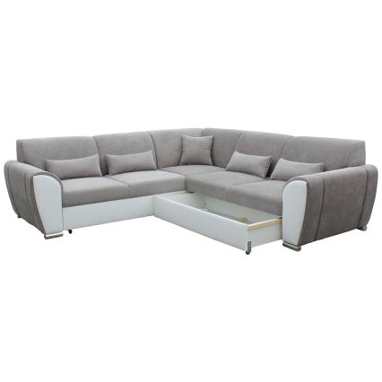 Rohová sedačka s výsuvným úložným priestorom je umiestnená na bielom pozadí. Sedačka je čalúnená sivou látkou a bielou koženkou. Je vybavená viacerými vankúšmi.