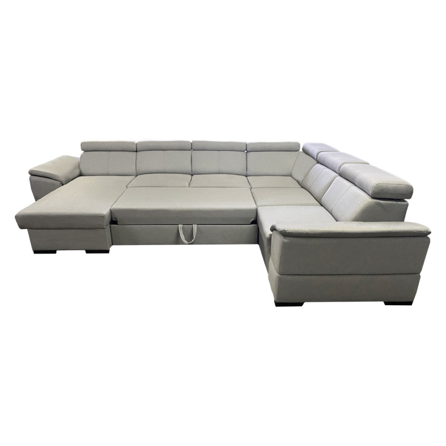 Rohová sedačka s rozkladacím lôžkom je umiestnená na bielom pozadí. Sedačka je svetlošedá, má mnoho častí a je tvarovaná do písmena L. Súčasťou je úložný priestor.