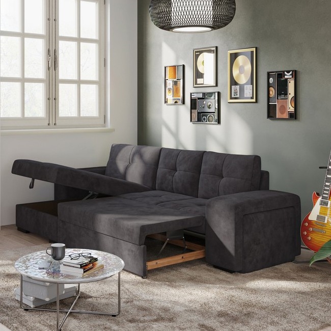 Rohová sedačka s ľavostranným kreslom a taburetkou stojí na bielom pozadí. Sedačka je tmavosivá a čalúnená. Má čalúnené podrúčky a je rozdelená do modulov.