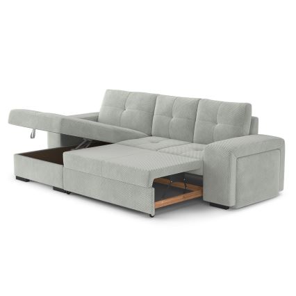 Rohová sedačka s rozkladacím lôžkom je čiastočne rozložená, odhaľujúc úložný priestor. Sedačka je svetlozelená s čalúnením z textílie. Na pozadí je biele pozadie.