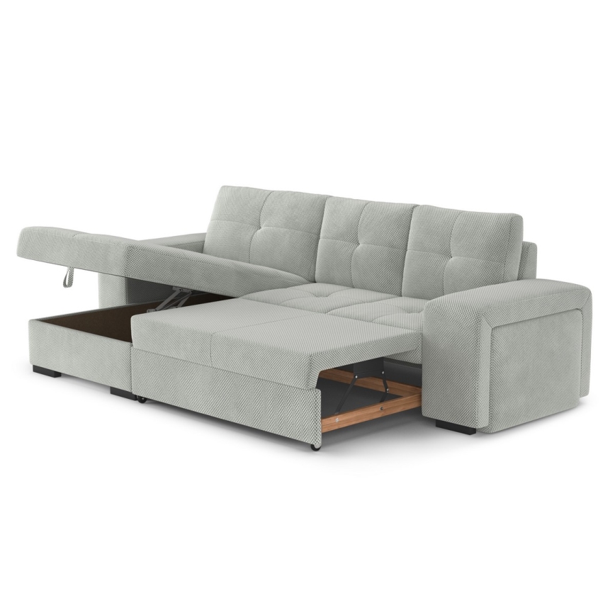 Rohová sedačka s rozkladacím lôžkom je čiastočne rozložená, odhaľujúc úložný priestor. Sedačka je svetlozelená s čalúnením z textílie. Na pozadí je biele pozadie.