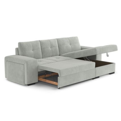 Rohová sedačka s rozkladacím lôžkom a úložným priestorom je čiastočne rozložená. Je svetlošedá, čalúnená látkou s jemnou štruktúrou. Nachádza sa na bielom pozadí.