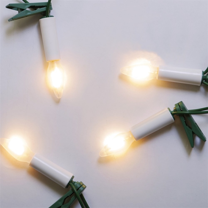 Pätica rozžiarených svetielok s bielymi plastovými objímkami a zelenými plastovými sponami je rozložená na bielom pozadí. Svietidlá sú pripojené k elektrickému káblu.