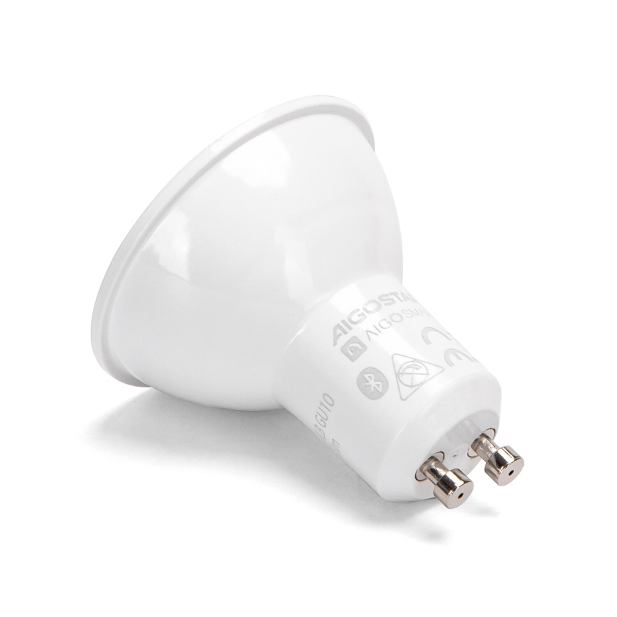 LED žiarovka GU10 leží na bielom pozadí. Na jej spodnej časti je viditeľné označenie: AIGOSTAR, AIGOSTAR SMART, symboly Bluetooth, zakázaného zdroja tepla a CE.