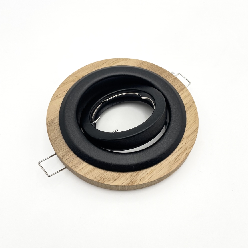 Svietidlový rám s čiernym vnútorným krúžkom a dreveným vonkajším krúžkom leží na bielom podklade. Rám má dva kovové háčiky.