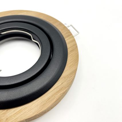 Drevený rám s čiernym vnútorným krúžkom a kovovým držiakom sa nachádza na bielom pozadí. Rám je okrúhly, vyrobený z dreva a má čierny plastový vnútorný krúžok. Malý kovový držiak je umiestnený na boku.