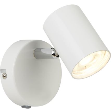 Biela nástenná lampa s valcovým tienidlom a chrómovým ramenom svieti. Lampa je pripevnená na stene.