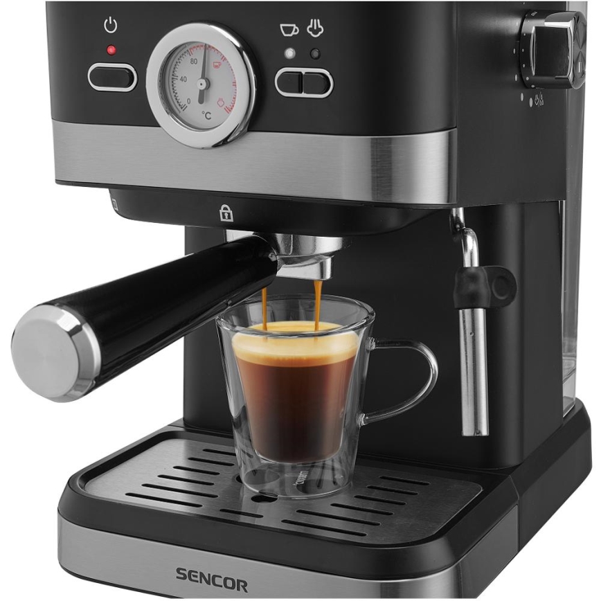 Espresso kávovar Sencor pripravuje espresso do sklenenej šálky. Kávovar je prevažne čierny s kovovými prvkami a má ovládací panel s teplomerom.