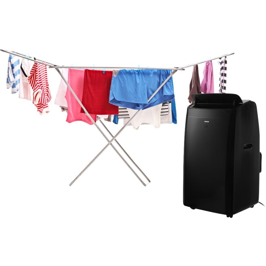 Mobilná klimatizácia stojí vedľa stojana na bielizeň, na ktorom suší prádlo. Na stojane visí niekoľko kusov farebného oblečenia.
