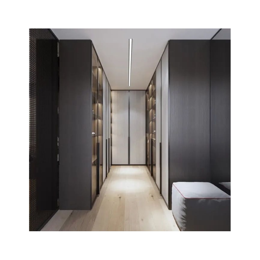 Šatník s tmavými skriňami a presklenými policami sa rozprestiera po oboch stranách dlhej chodby s svetlou drevenou podlahou a stropným osvetlením. Na konci chodby je svetlý panel. Pri stene je umiestnený mäkký sedací puf.