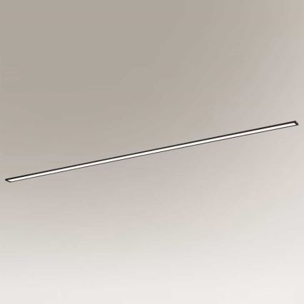 Dlhá tenká LED lampa je umiestnená vodorovne pred svetlohnedým pozadím. Lampa svieti.