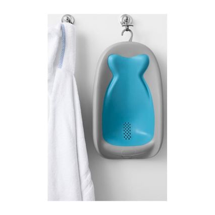 Detská vanička visí na háku na stene. Je svetlomodrej a šedosivej farby. Vedľa nej visí biely uterák.