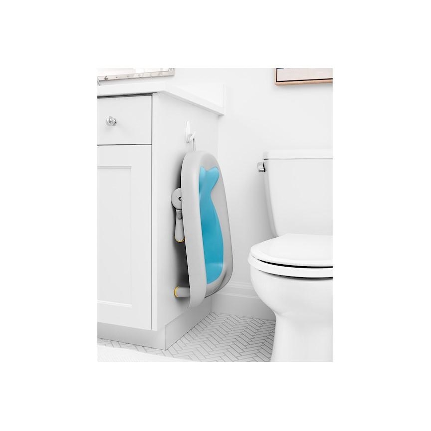 Detská vanička v tvare ryby je zavesená na háčiku na skrinke v kúpeľni. Vanička je svetlosivá s vnútornou modrou časťou. Nachádza sa vedľa toalety.