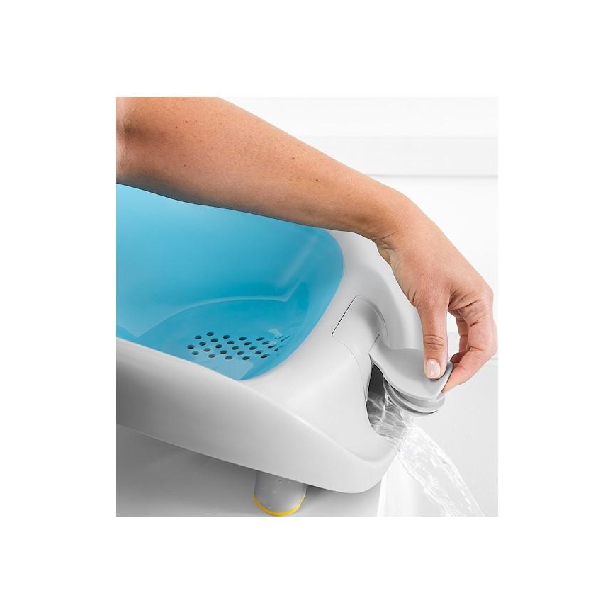 Ruka otvára odtok modrobielych detských vaničiek, z ktorých vyteká voda. Vanička je umiestnená v kúpeľni.