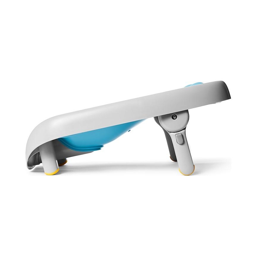 Prebaľovací pult s vaničkou je zobrazený v bočnom profile. Pult je šikmo postavený, má svetlosivú a svetlomodrú farbu a je vybavený nožičkami s protišmykovými koncovkami.