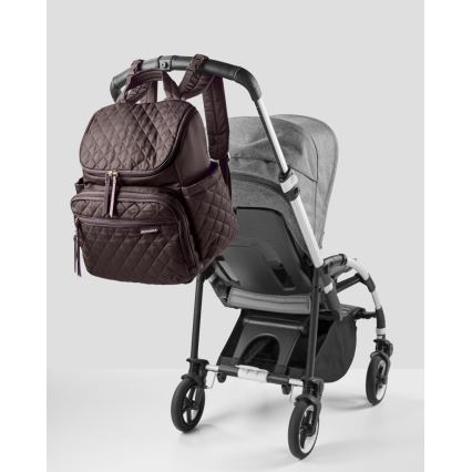 Hnedá prebaľovacia taška-batoh visí na rukoväti detského kočíka. Kočík je sivý a tmavošedý, má štyri kolesá. Taška je prešívaná.