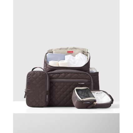 Hnedá prebaľovacia taška-batoh je naplnená detskými vecami. K nej patria menšie hnedé doplnkové taštičky, jedna s priehľadnou sieťkou. Taška a taštičky sú prešívané.