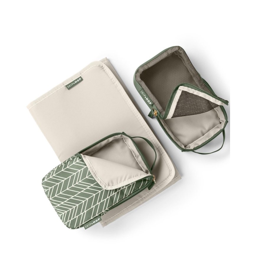 Plienková podložka a tri otvorené cestovné taštičky ležia na bielom pozadí. Taštičky sú zelené s béžovou podšívkou, jedna má vzor do šípky. Na všetkých taštičkách je logo SKIP HOP.