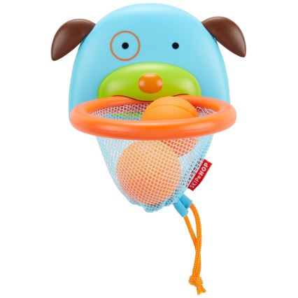 Plastová hračka v tvare hlavy psa má pripevnenú košíkovú sieť s dvoma oranžovými loptičkami. Hračka je určená na hádzanie loptičiek. Na sieti je logo SKIP HOP.