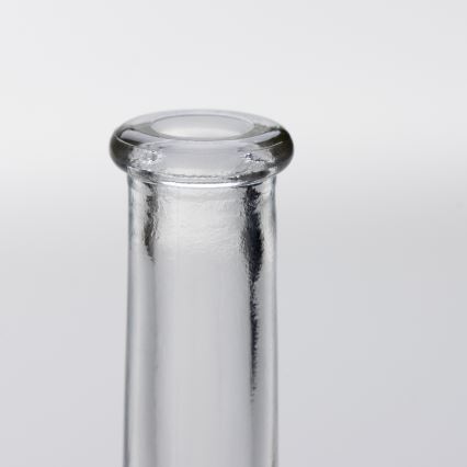 Sklenená fľaša stojí na svetlom pozadí. Je zobrazená horná časť fľaše, s kruhovým otvorom na vrchu. Fľaša je priehľadná.