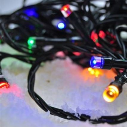 Elektrický svetelný veniec s farebnými LED diódami leží na bielom povrchu, ktorý pripomína umelý sneh. Diody svietia v rôznych farbách: červená, zelená, modrá, oranžová a fialová.