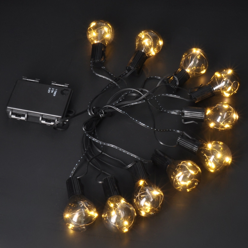 Svetlá s desiatimi guľôčkovými žiarovkami svietia žltým svetlom. Sú pripojené k čiernemu batériovému boxu s popisom: 1.TIMER, 2.ON, 3.OFF. Všetko je rozložené na tmavom povrchu.