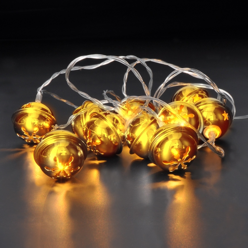 Svetlá v tvare zlatých zvončekov svietia na tmavom povrchu. Zvončeky sú prepojené priesvitným káblom. Tvoria svetelnú dekoráciu.