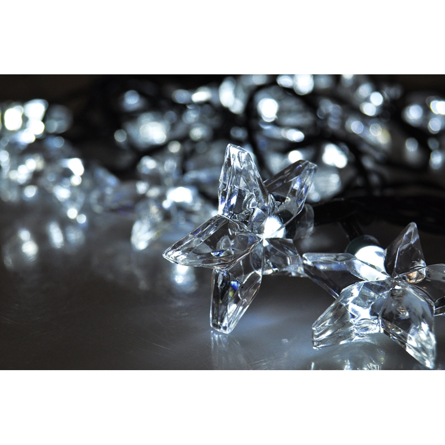 Svetlené hviezdice v tvare kryštálov svietia na tmavom povrchu. Sú súčasťou svetelnej reťaze. Hviezdice sú pripevnené k tenkému čiernemu káblu.