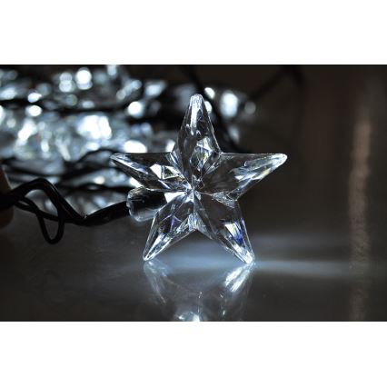 Hviezdna LED svetelná reťaz s priehľadnými hviezdami svieti na tmavom povrchu. Jedna hviezda je v popredí, ostatné sú rozostrené v pozadí.