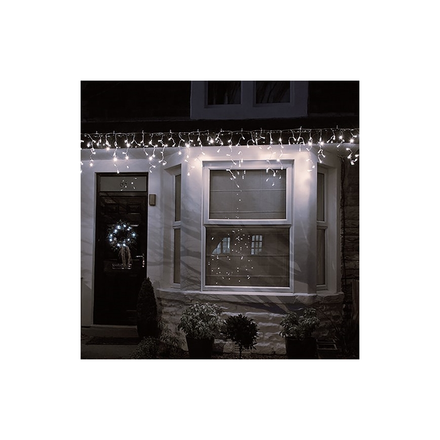 Svetlá v tvare rampúch osvetľujú dom. Sú umiestnené nad oknami a dverami domu v noci. Na dverách je veniec.