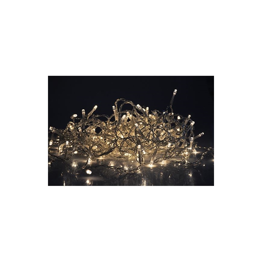 Elektrický svetelný girlandový veniec s mnohými malými žiarovkami s teplým bielym svetlom je zvráskavený na tmavom pozadí, odráža sa na lesklom povrchu.