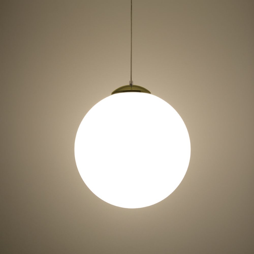 Guľová lampa visí zo stropu. Svieti. Stena je svetlohnedá.