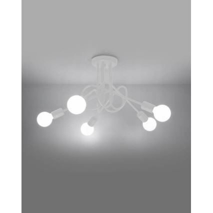 Biela stropná lampa s piatimi žiarovkami svieti. Jej ramená sú prepletené a vychádzajú z kruhovej základne pripevnené k stropu. Lampa je v svetlej miestnosti.