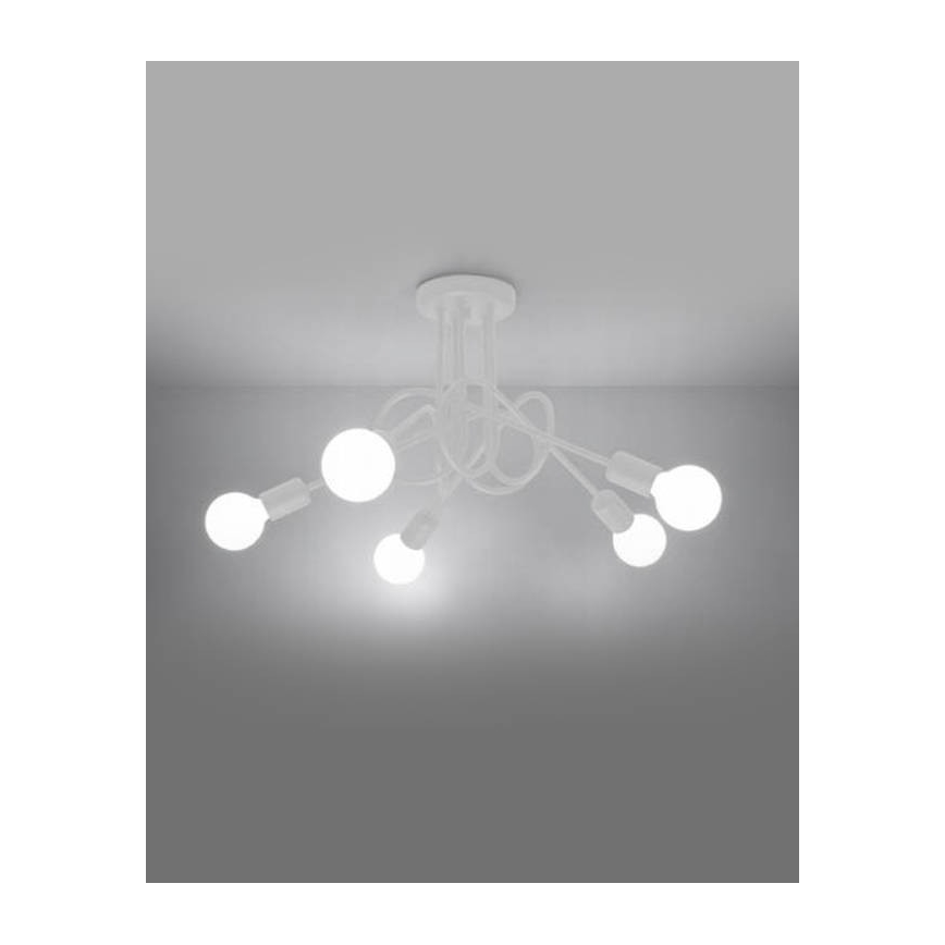 Biela stropná lampa s piatimi žiarovkami svieti. Jej ramená sú prepletené a vychádzajú z kruhovej základne pripevnené k stropu. Lampa je v svetlej miestnosti.