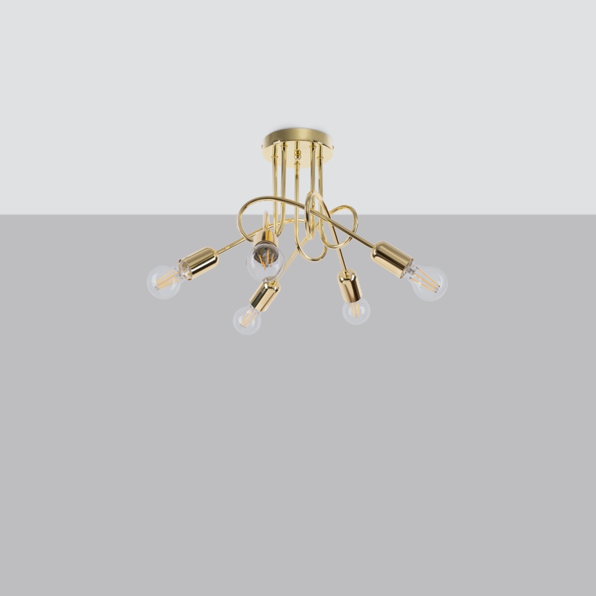 Zlatá stropná lampa s piatimi žiarovkami visí z plochého stropu. Žiarovky sú pripevnené na ozdobných, zakrivených ramenách. Lampa je umiestnená na neutrálnom sivom pozadí.