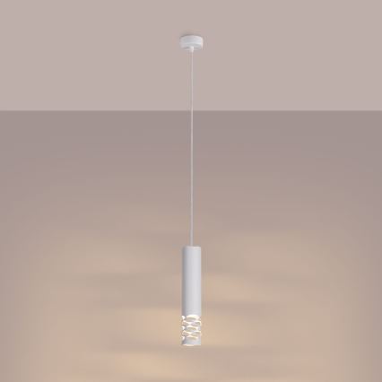 Biela valcovitá závesná lampa s otvormi v strede svieti. Je zavesená na šnúrke z bieleho stropu na svetlohnedom pozadí.