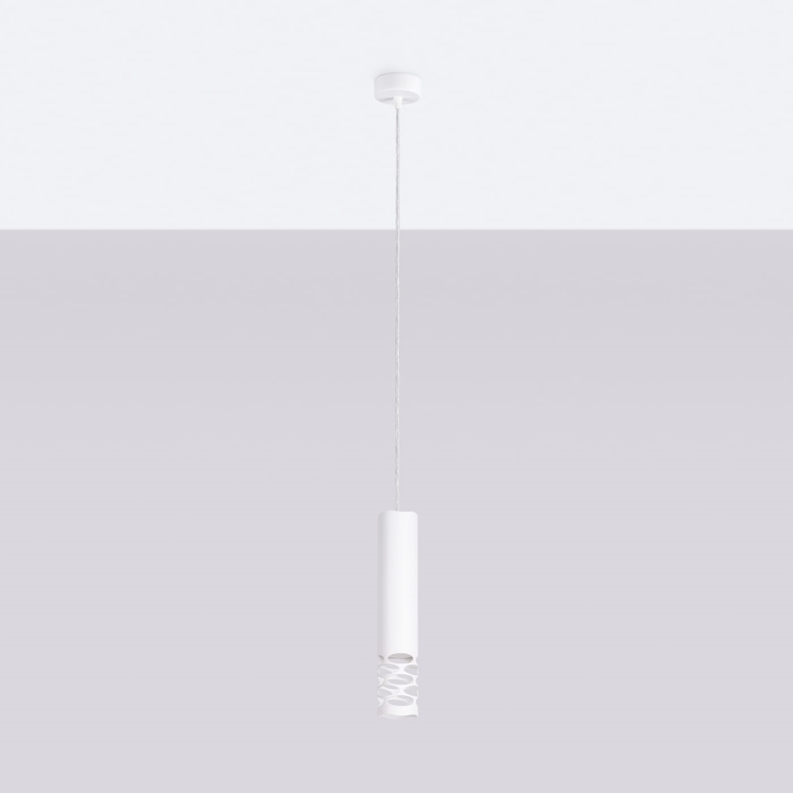 Biela závesná lampa s valcovitým tienidlom, ktoré má v strede perforáciu, visí zo stropu pred svetlosivou stenou.